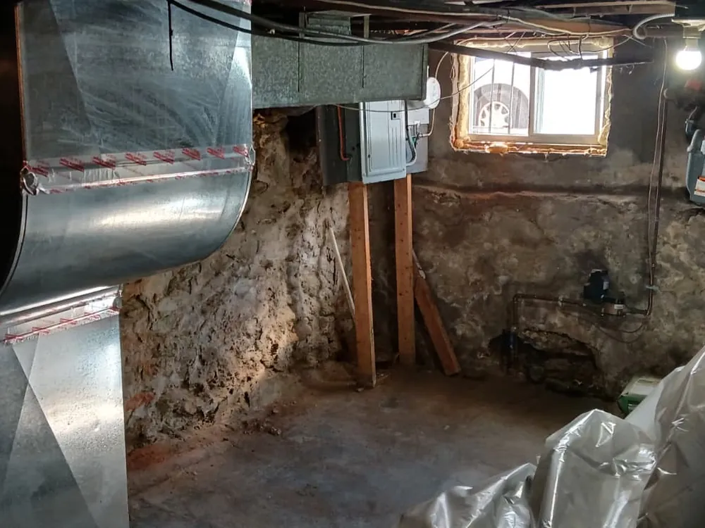Old rough stone foundation wall in a basement before waterproofing